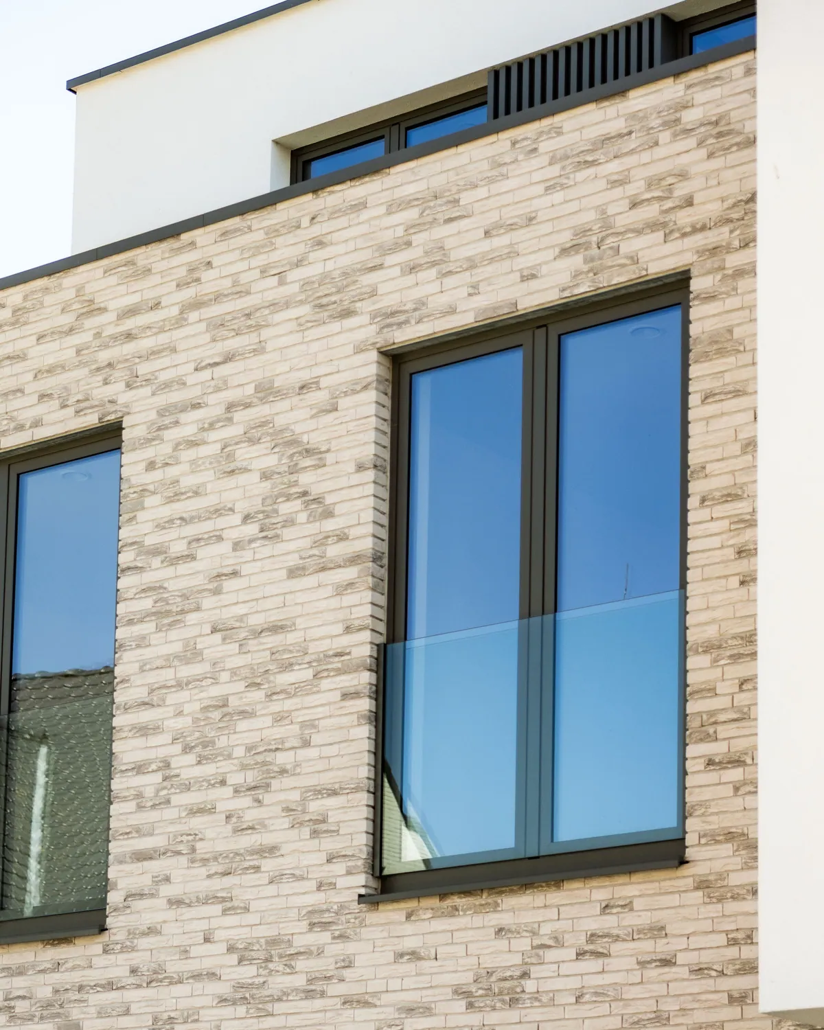 Antraciet aluminium ramen met glazen balustrade in lichte gevelsteen