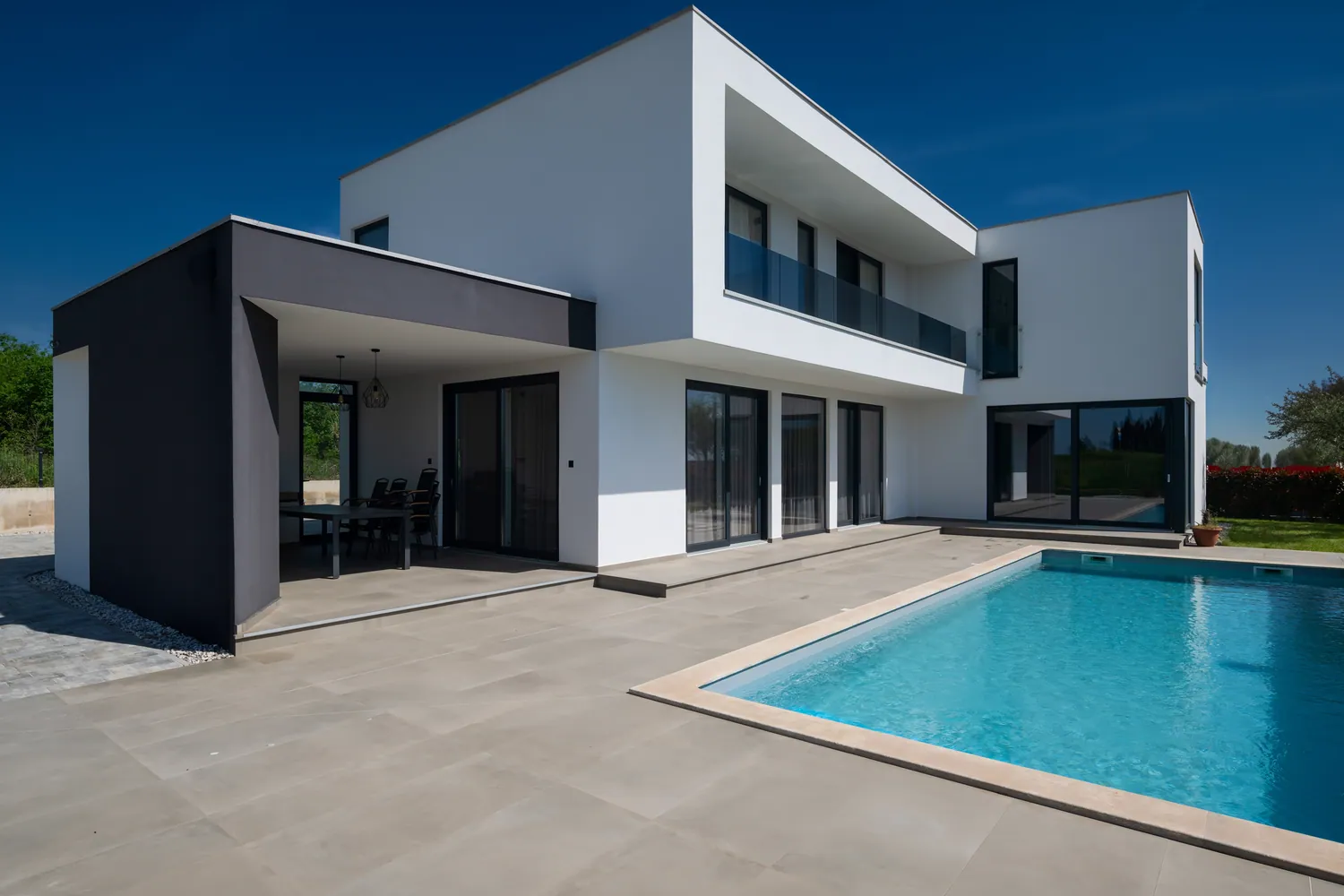 Witte villa met grote donkere schuiframen aan het zwembad