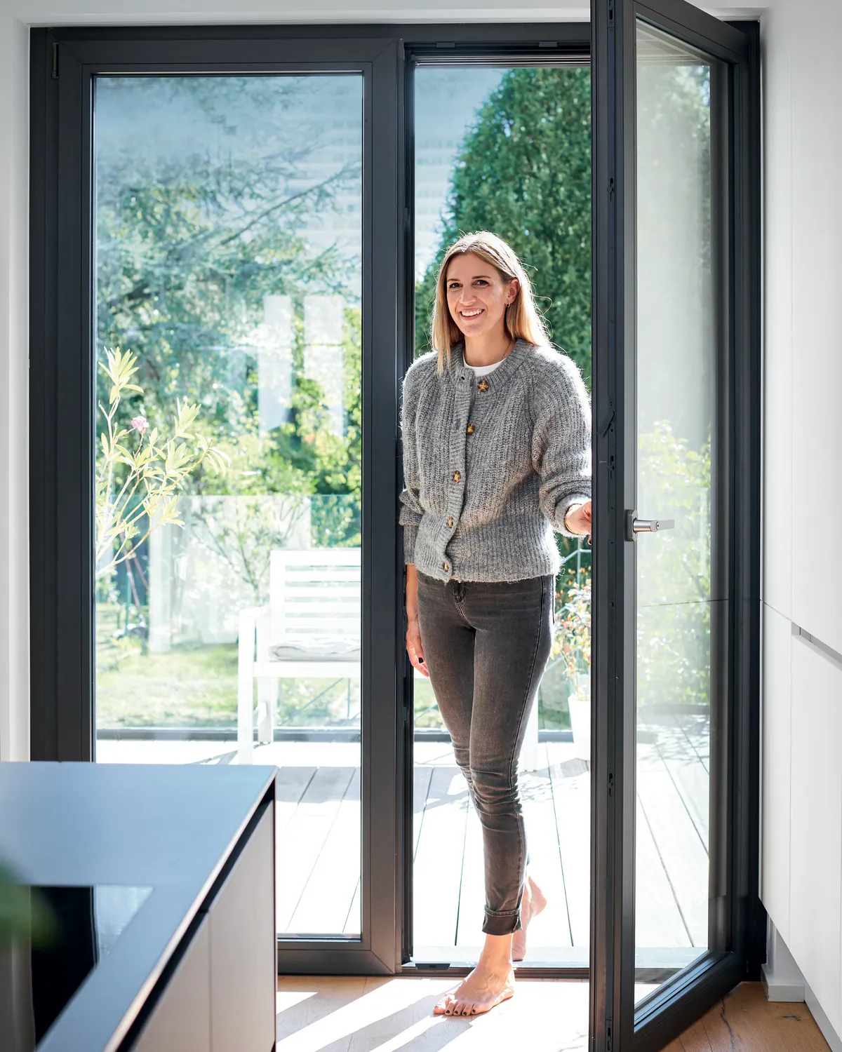 Vrouw opent een antraciet terrasdeur naar het terras